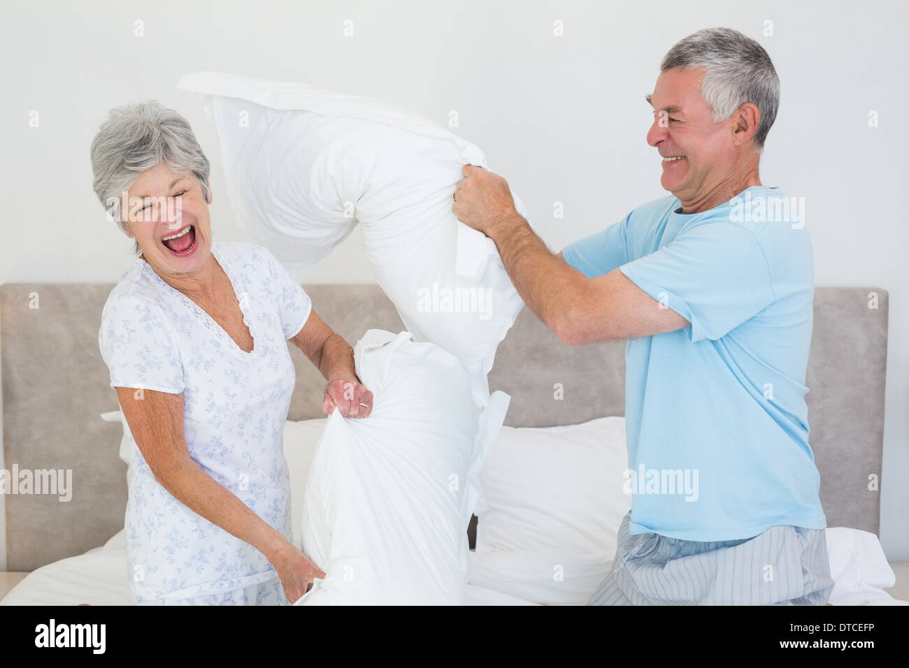Senior couple having pillow fight in bed Stock Photo