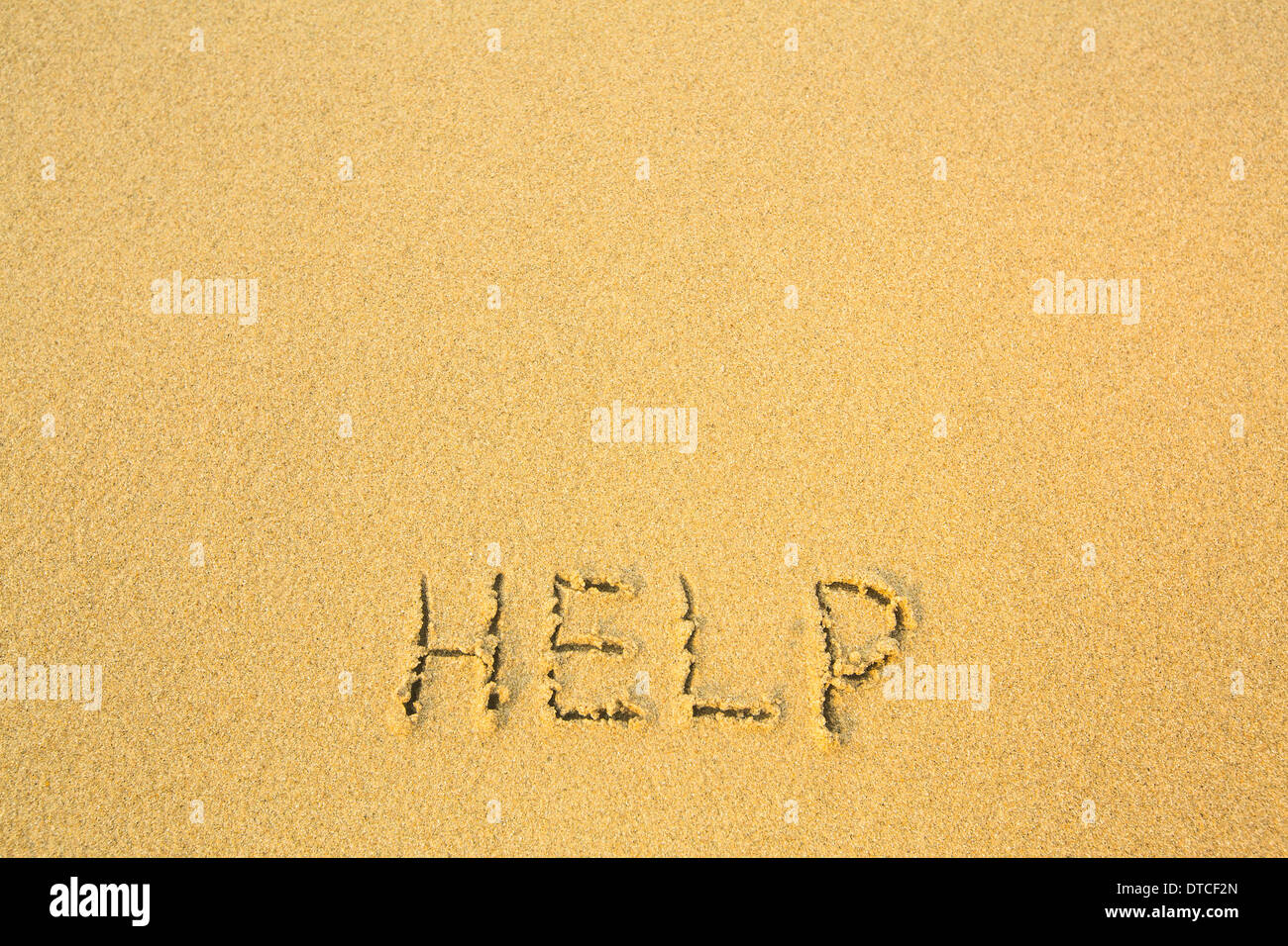Help - written in sand on beach texture Stock Photo - Alamy