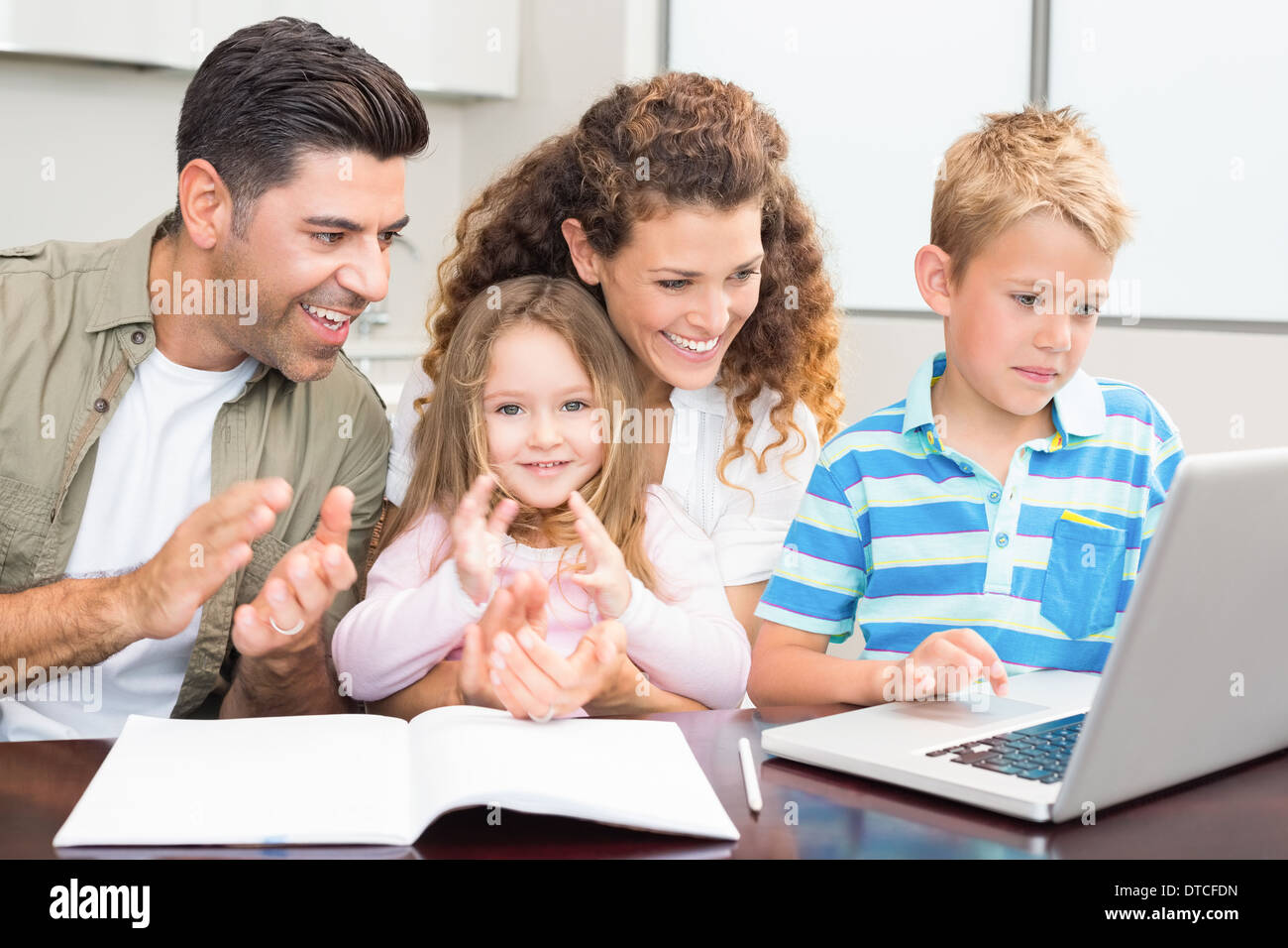 Happy parents using laptop with their young children Stock Photo - Alamy