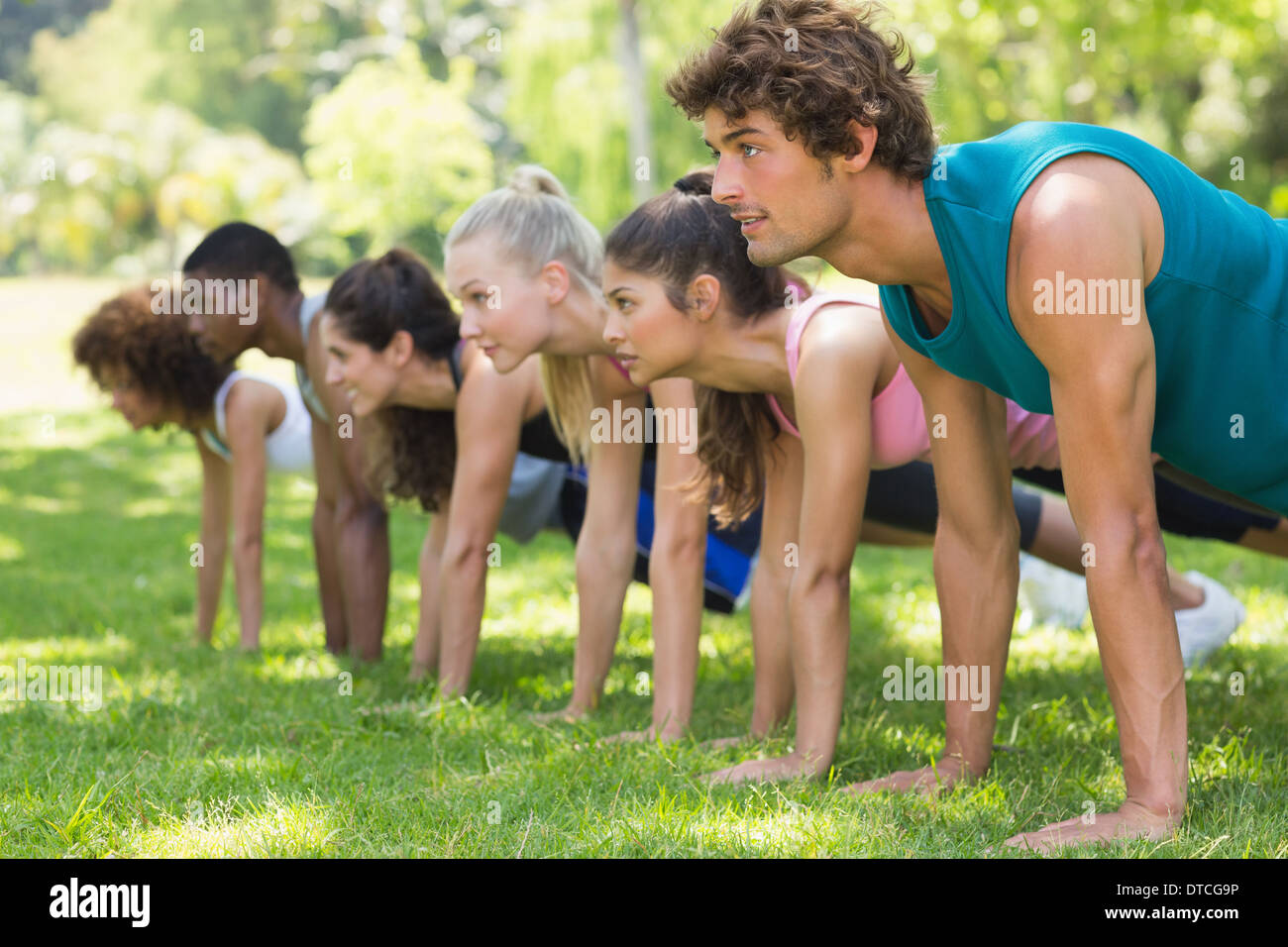Group of fitness people doing push ups in park Stock Photo