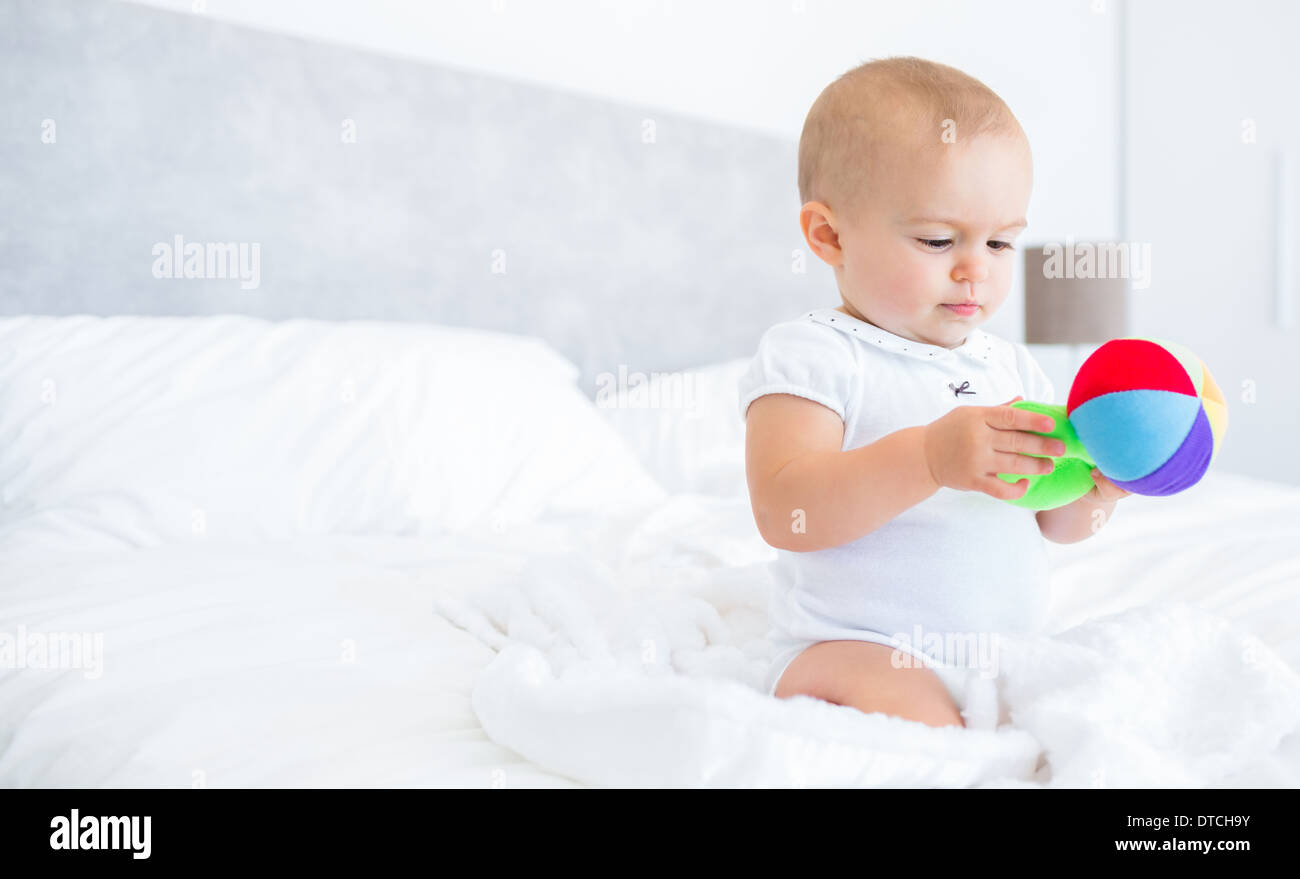 Cute baby with toy sitting on bed Stock Photo