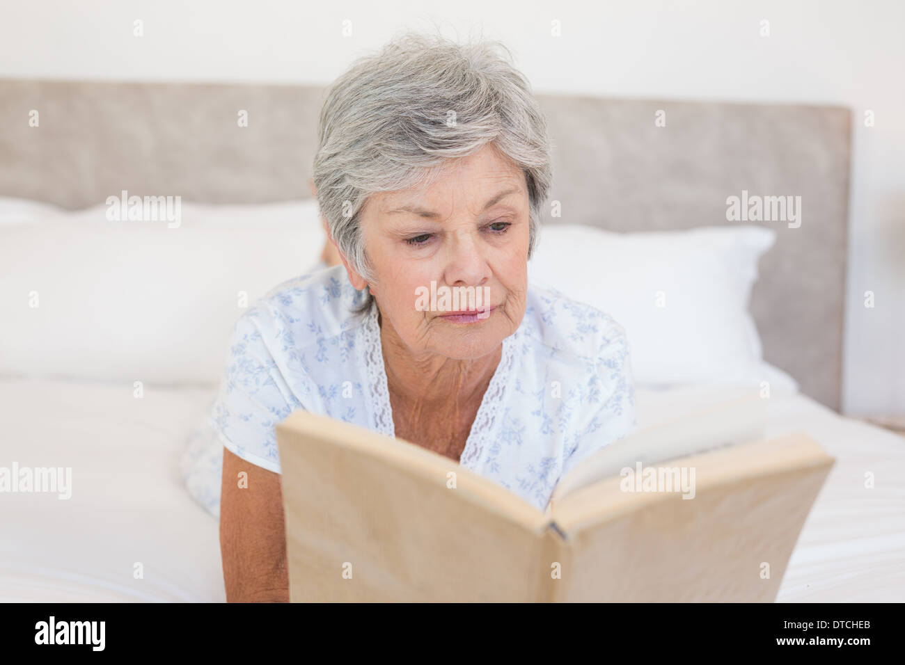 Senior woman reading story book in bed Stock Photo