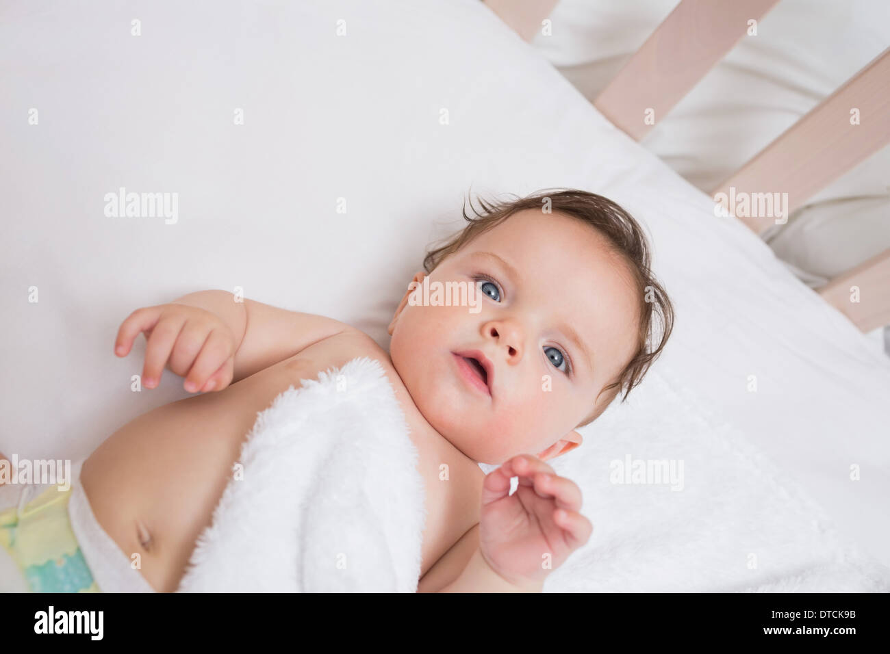 Adorable baby lying in crib Stock Photo