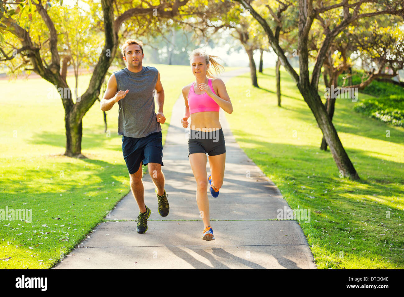 Athletic couple running together. Sport runners jogging on park trail in the early morning. Healthy lifestyle fitness concept Stock Photo