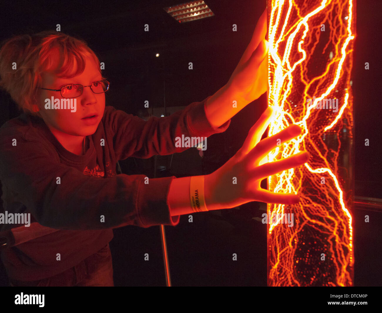 A 12-year old boy is experimenting with an electric plasma captured in a glass tube. Stock Photo