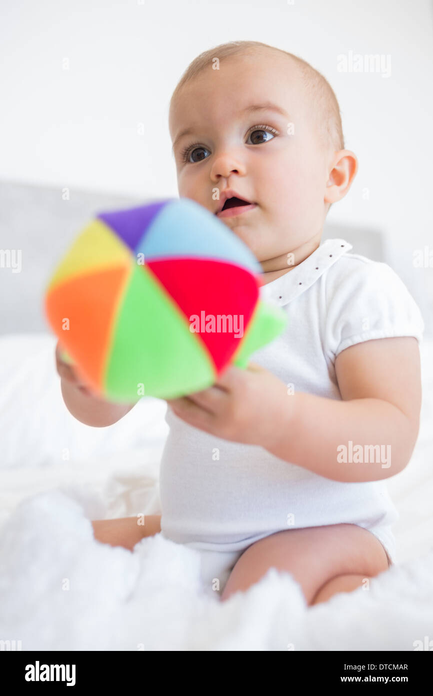 Cute baby with toy sitting on bed Stock Photo