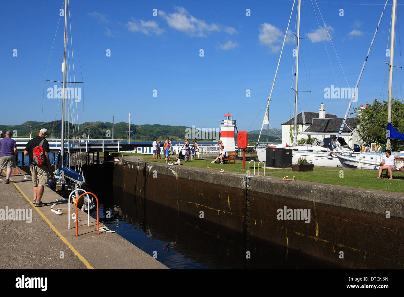 People at Crinan watching a yacht going through the last lock on the Crinan Canal before entering the Sound of Jura Stock Photo