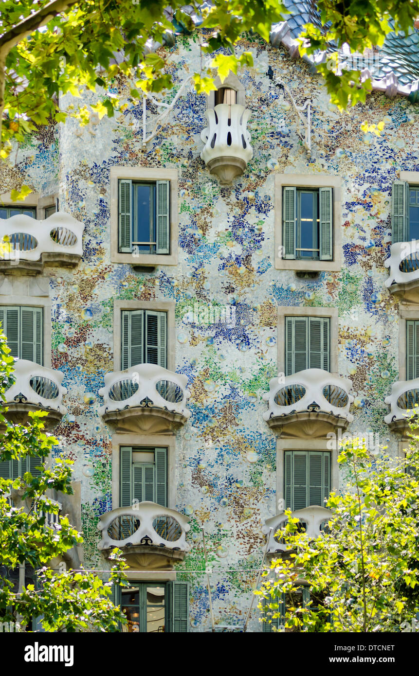 Architect Antonio Gaudi's Casa Batllo is framed by golden summer foliage in Barcelona. Stock Photo