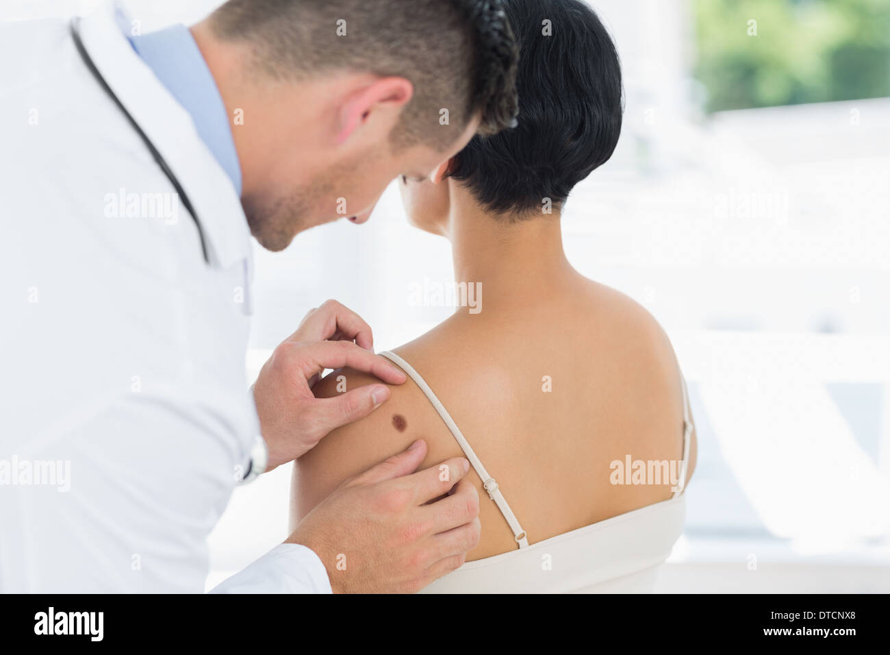 Doctor examining mole on back of woman Stock Photo