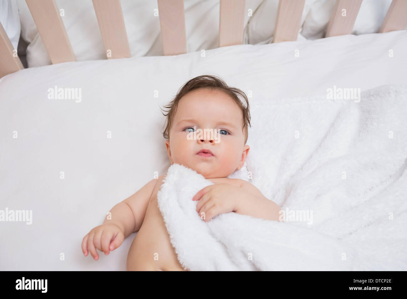 Baby with blanket in crib Stock Photo