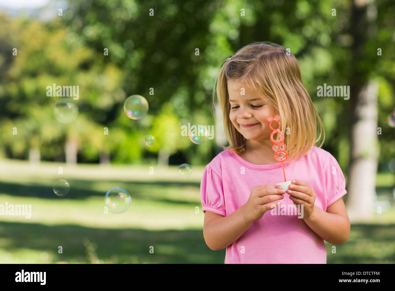 Cute girl is blowing soap bubbles in the garden Stock Photo - Alamy