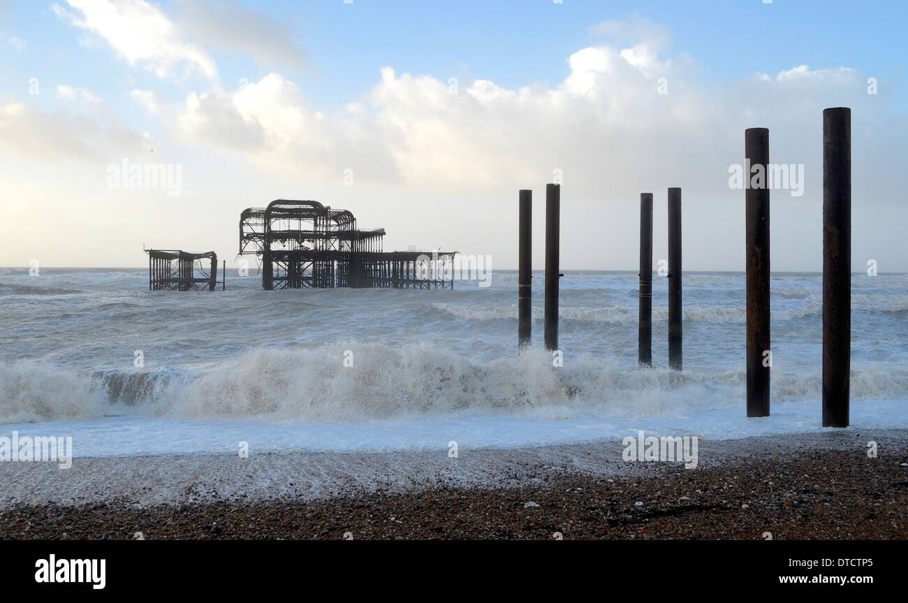 Brighton Hove seafront prom promenade winter storm pebbles railings beach huts bench benches waves crashing over path Stock Photo