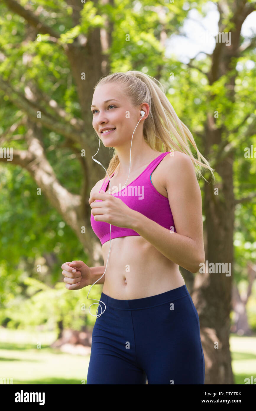 Healthy and beautiful woman in sports bra jogging in park Stock