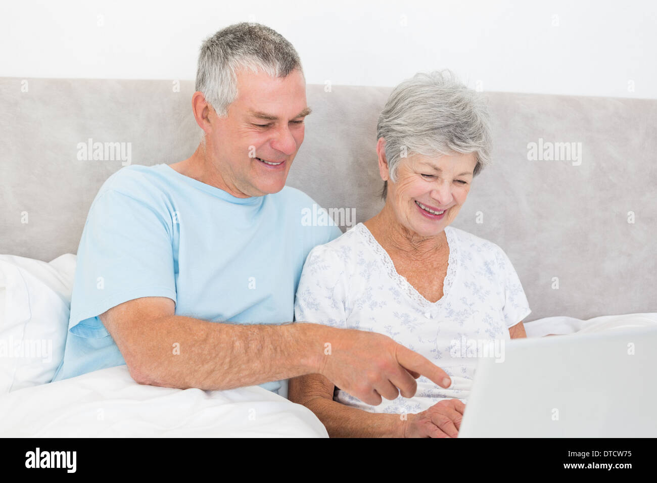 Senior couple using laptop in bed Stock Photo