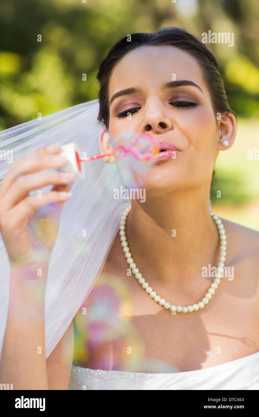 Beautiful bride blowing soap bubbles in park Stock Photo