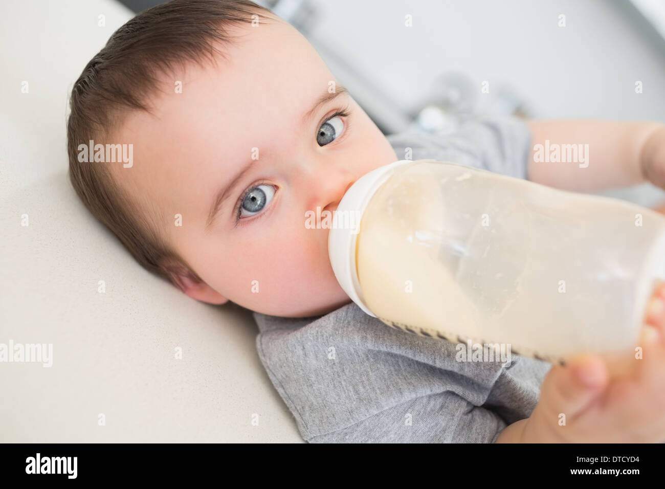 Baby drinking milk while lying on counter Stock Photo