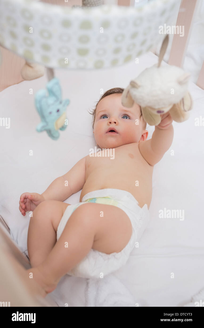 Adorable baby playing with toys in crib Stock Photo