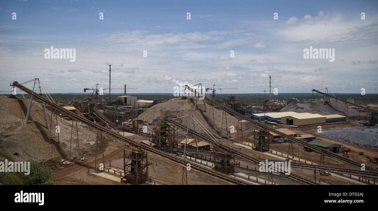 View over a a large open cast copper and gold processing plant with conveyor belts, cranes, crushed rock stockpiles and building Stock Photo