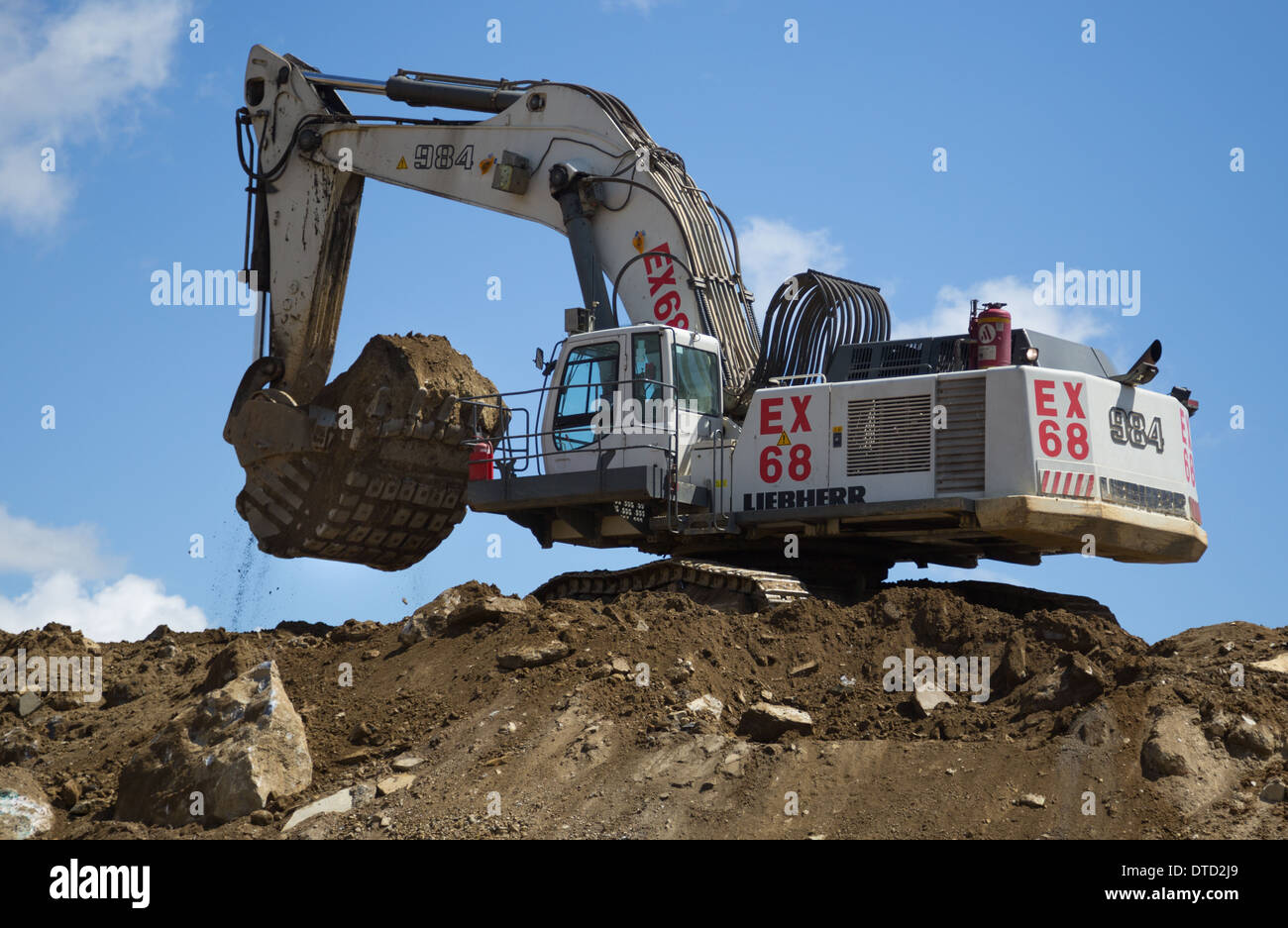 Excavator/ digger operator uses a Liebherr 984 to load oxide ore into the back of a mining dump truck for delivery to the plant.