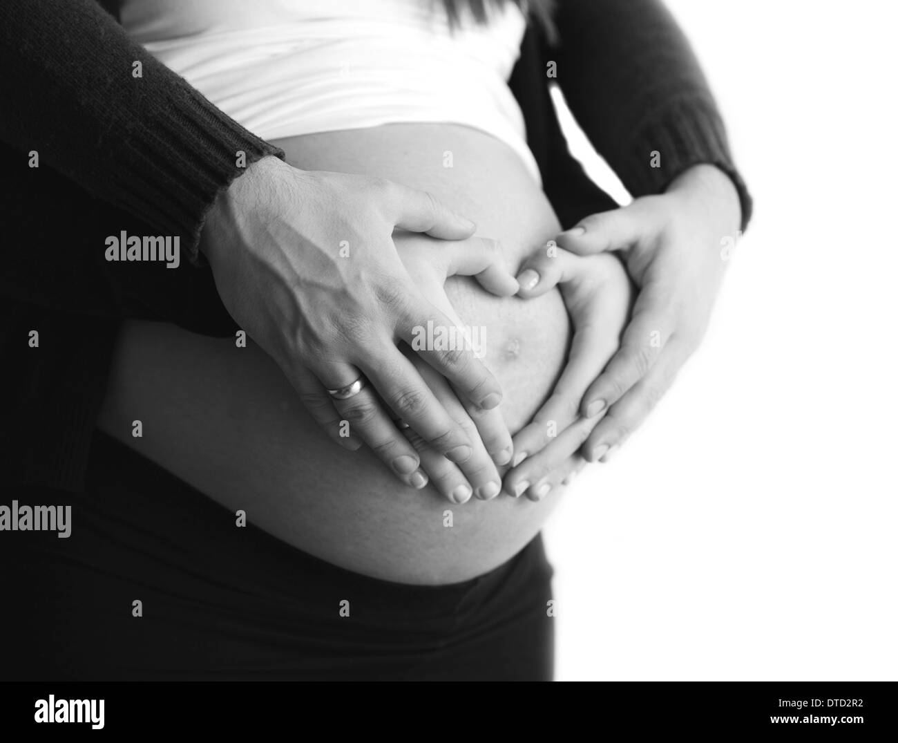 Pregnant couple with hands around belly making a heart shape Stock Photo