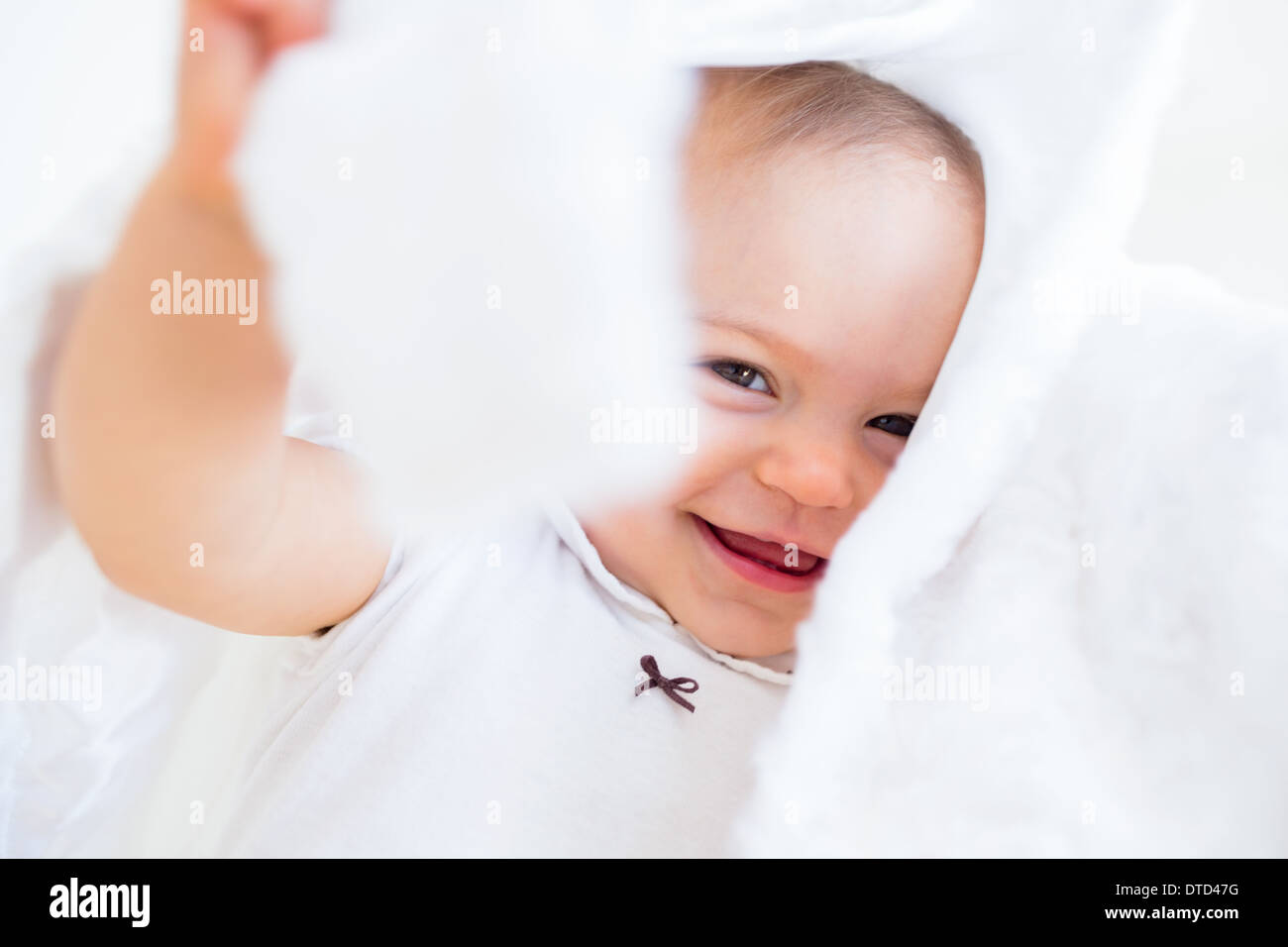 Closeup of a cheerful cute baby under comforter Stock Photo