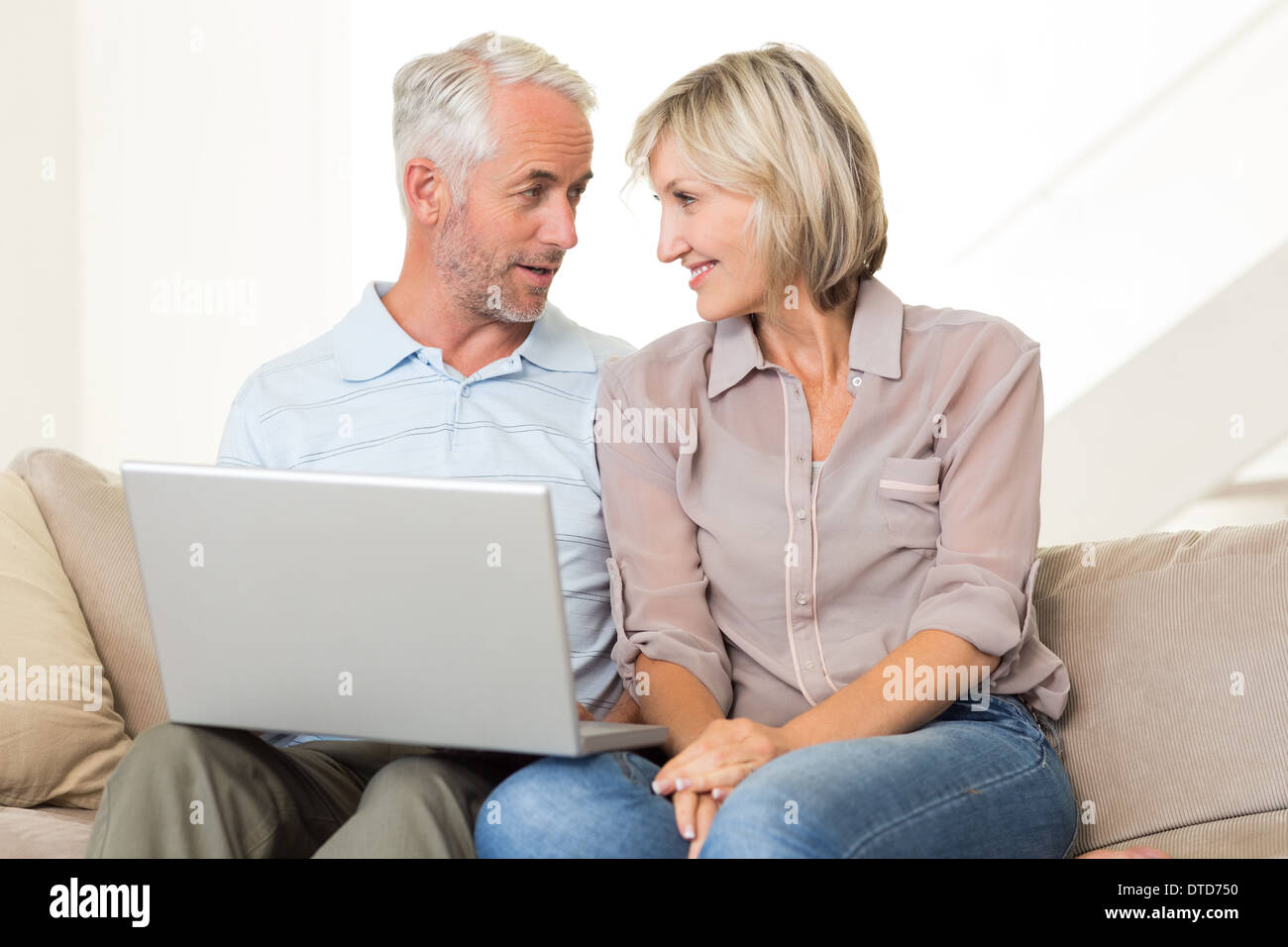 Happy mature couple using laptop on sofa Stock Photo