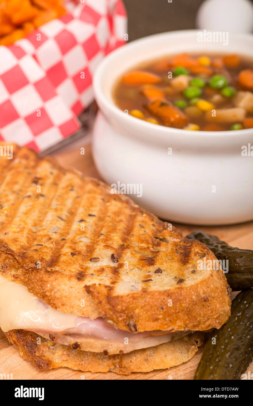 Freshly made ham, pork and swiss cheese panini served with vegetable soup and sweet potato fries. Stock Photo