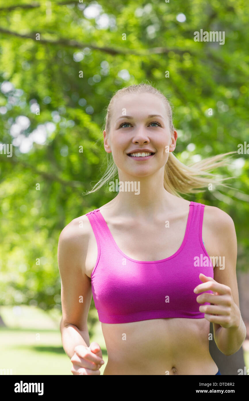 Healthy and beautiful woman in sports bra jogging in park Stock Photo