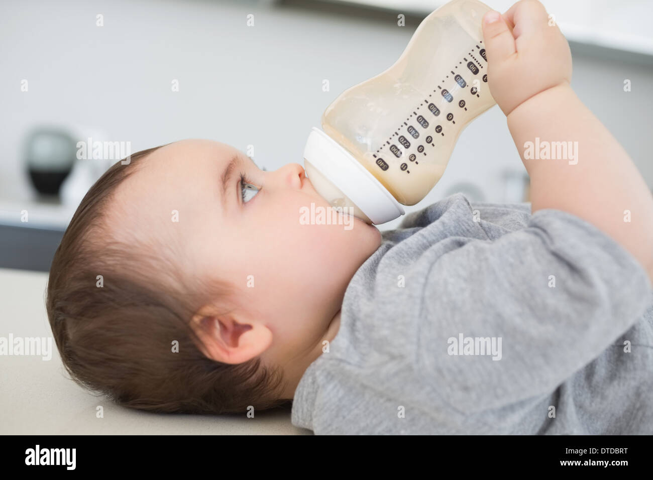 Baby drinking milk while lying on counter Stock Photo