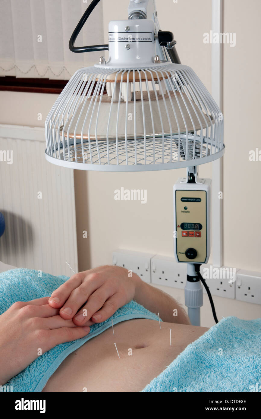 woman under heat lamp being used on acupuncture points Stock Photo Alamy