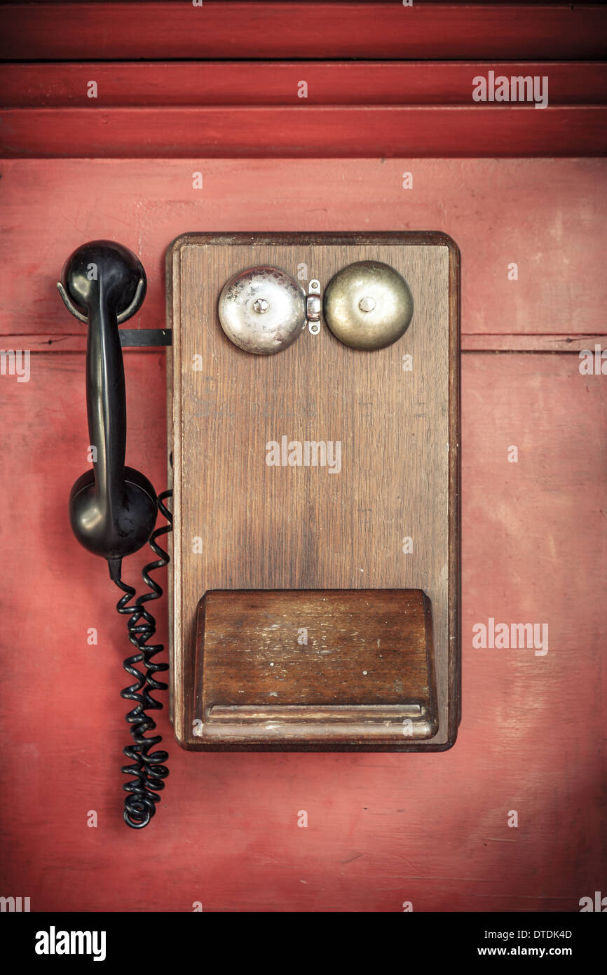 Antique wooden British Ericsson PMG Wall Phone mounted on a red wooden wall Stock Photo