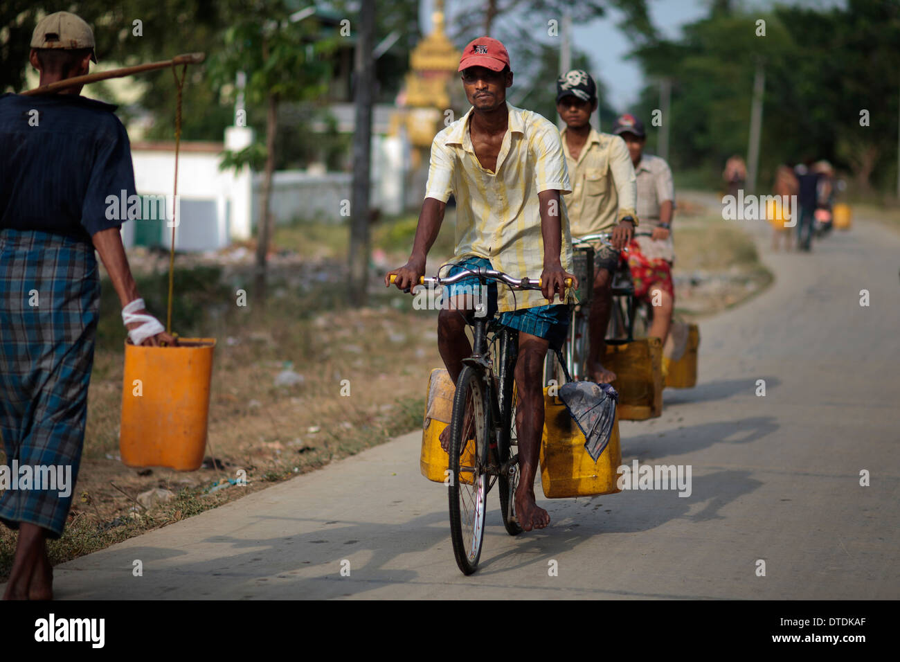 A man fill containers with water in a small lake in Dala Township, Myanmar, Monday, May 6, 2013 Stock Photo