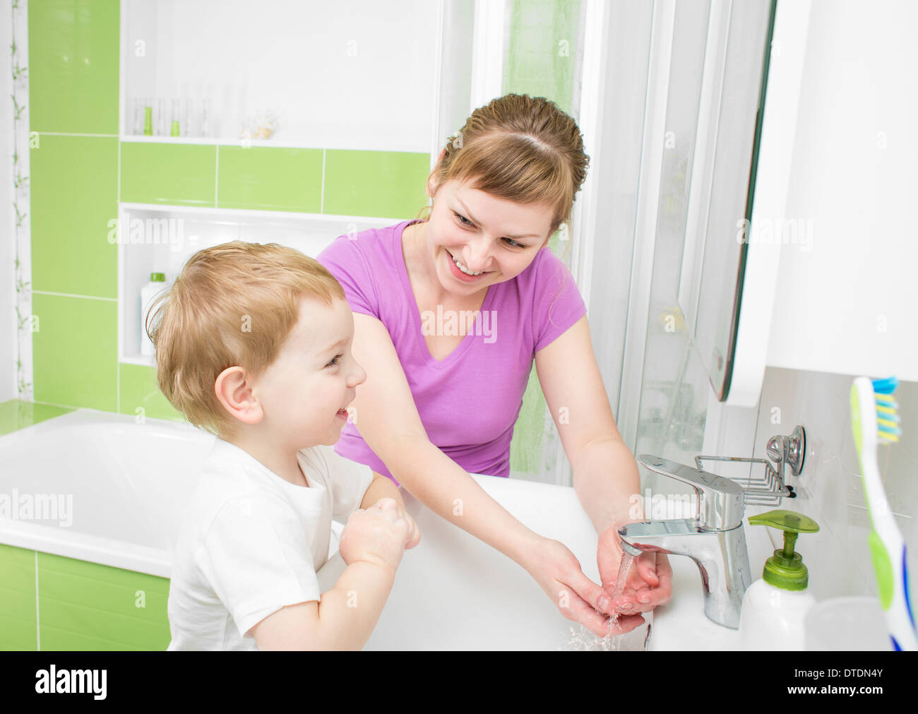Happy mother and kid washing hands with soap together in bathroom Stock Photo