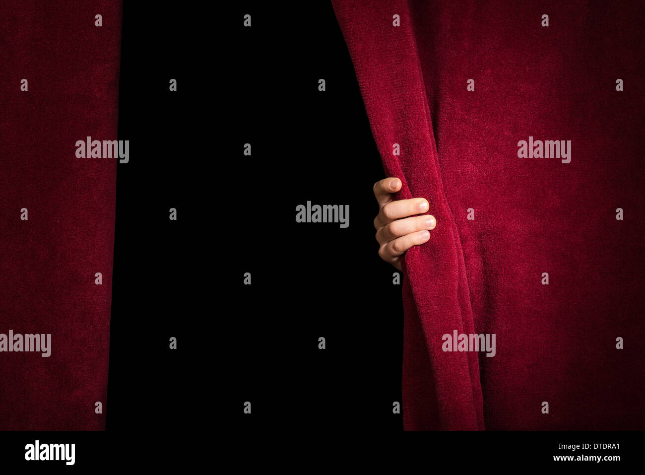 Hand appearing beneath the curtain. Red curtain. Stock Photo