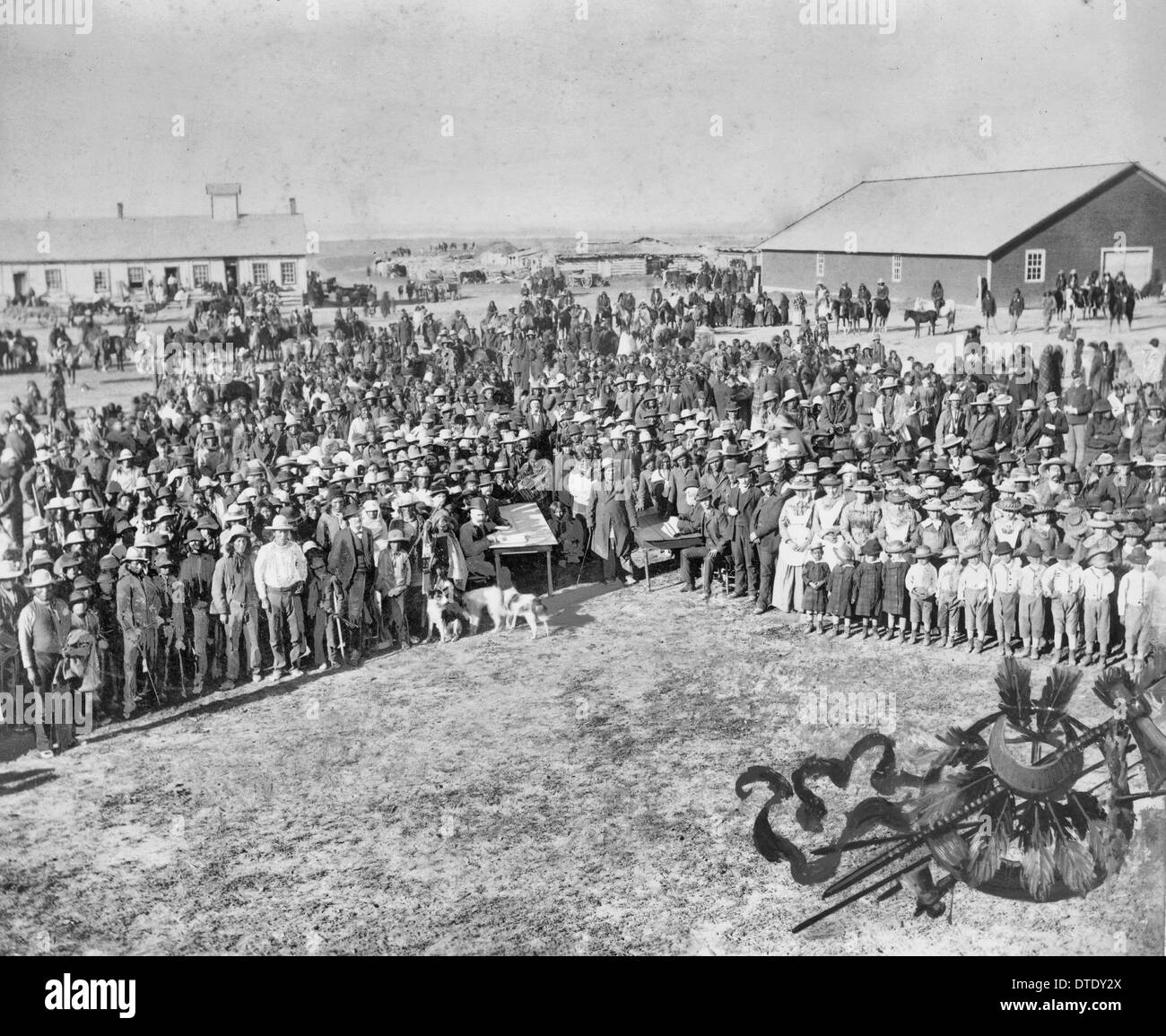 Taking the census at Standing Rock Agency - South Dakota - Men seated at two tables with large crowd of people. 1900 Stock Photo