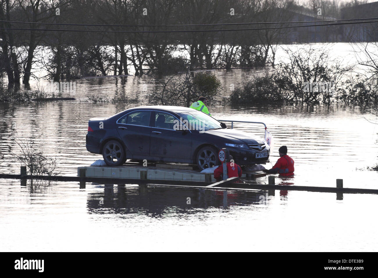 Burrowbridge, Somerset Levels Sunday 16th February 2014 – Unusual car rescue - volunteers use a floating pontoon to float a Honda Accord car from a cut off property - the pontoon was manhandled slowly and carefully to the nearest dry road. Stock Photo