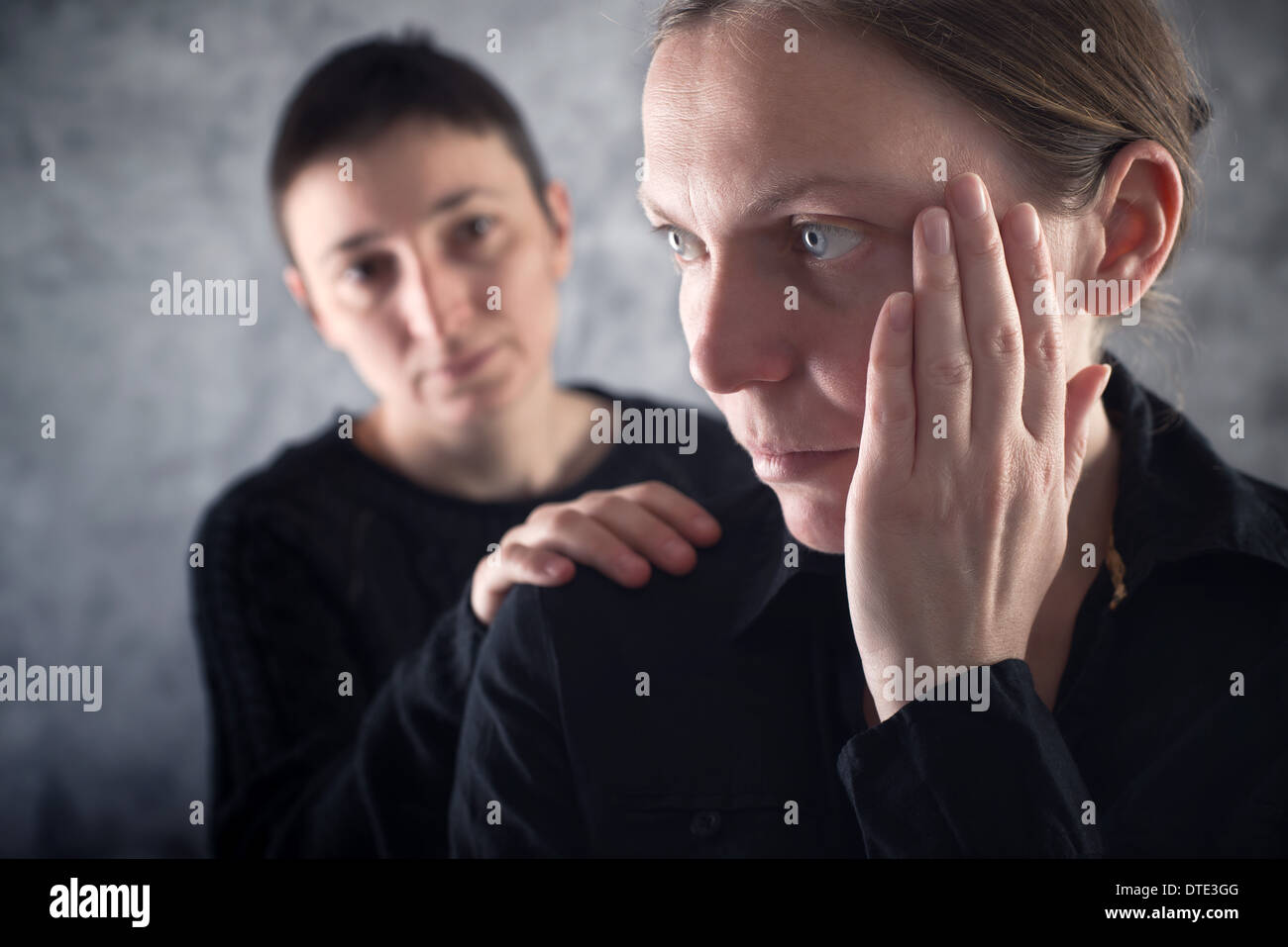 Comforting friend. Woman consoling her sad friend with hand on shoulder. Stock Photo