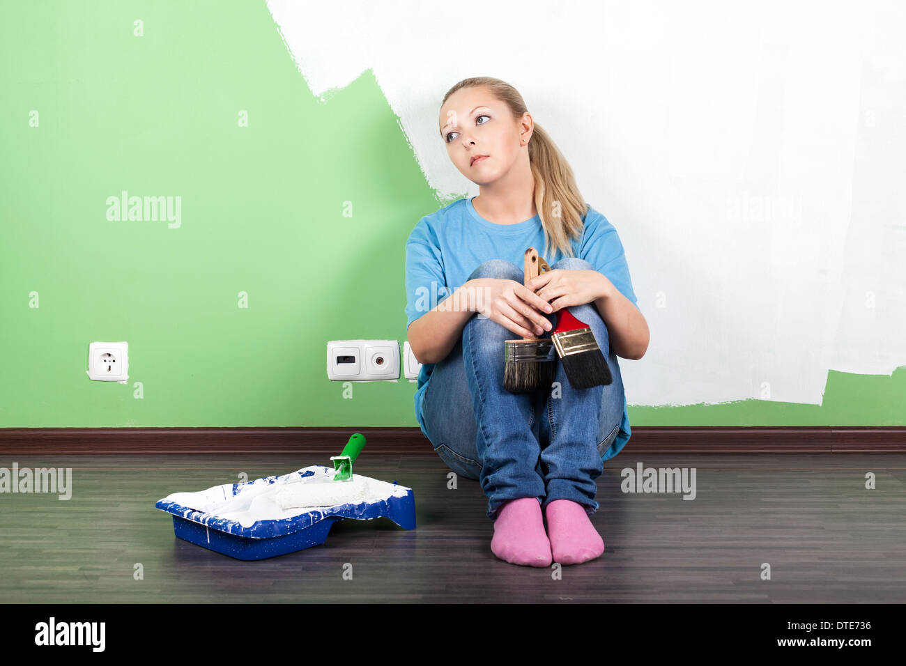 Unhappy woman with paint tools in hands Stock Photo