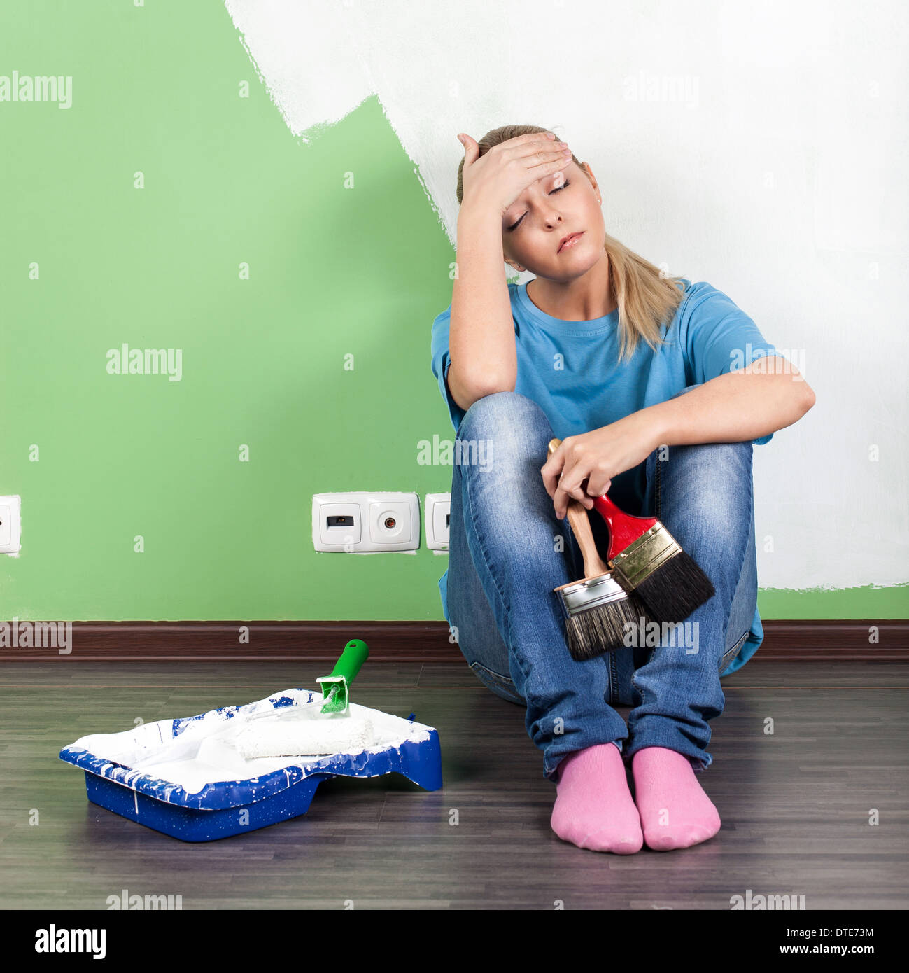 Tired woman with paint tools in hand Stock Photo