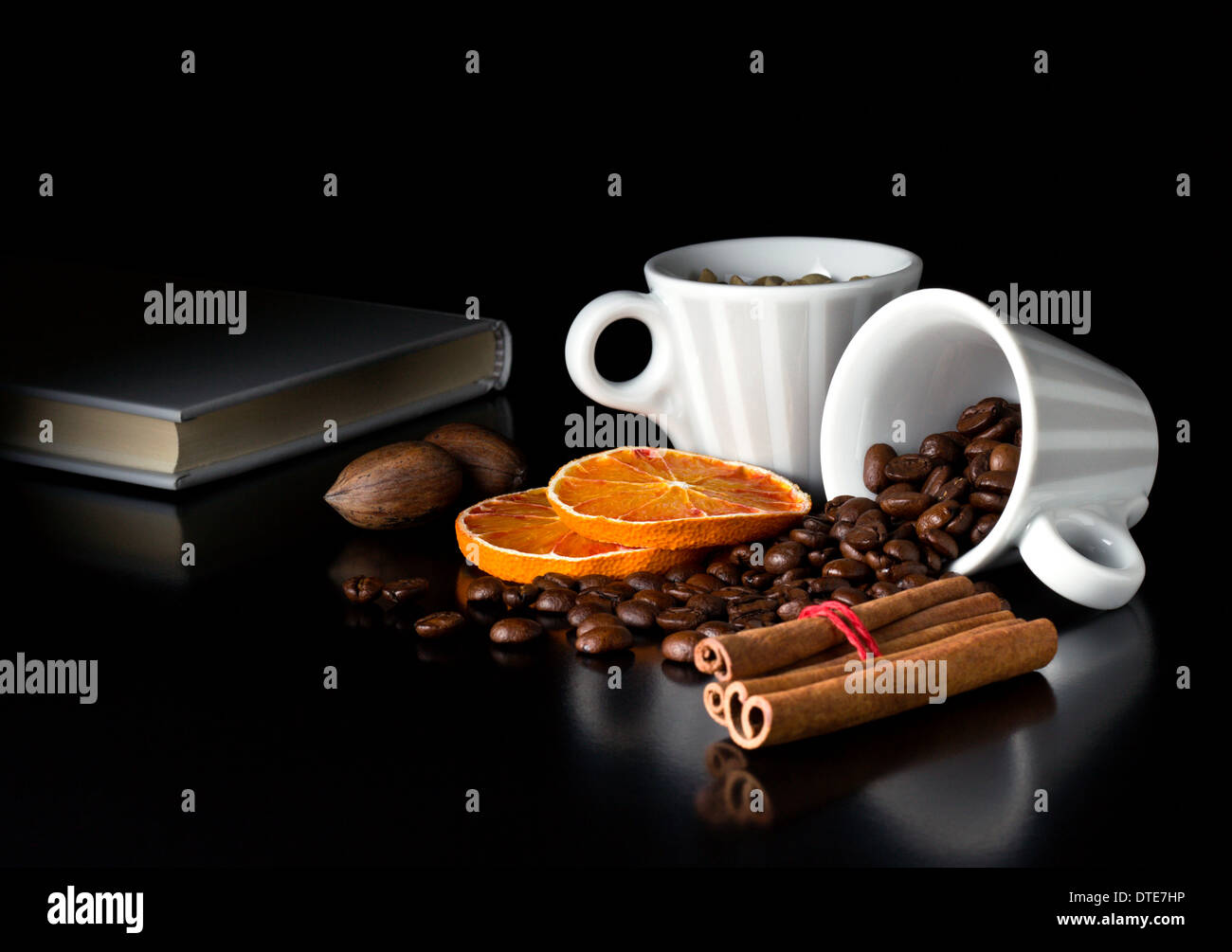 natural coffee beans with fruits and book on black table Stock Photo