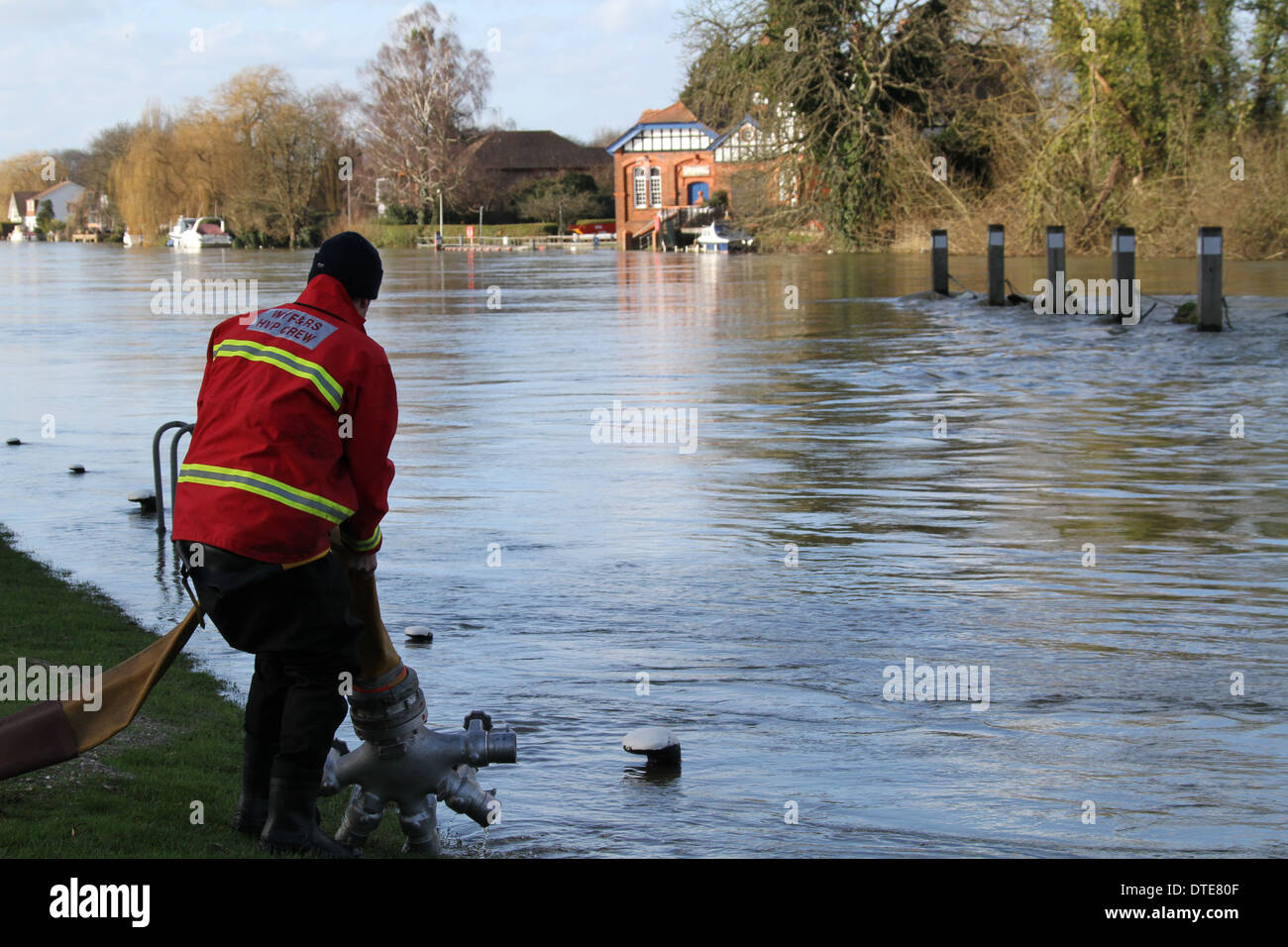 Firefighter inspects a hose laid to pump out floodwaters from Runnymede into the Thames at Bell Wier Lock. Stock Photo