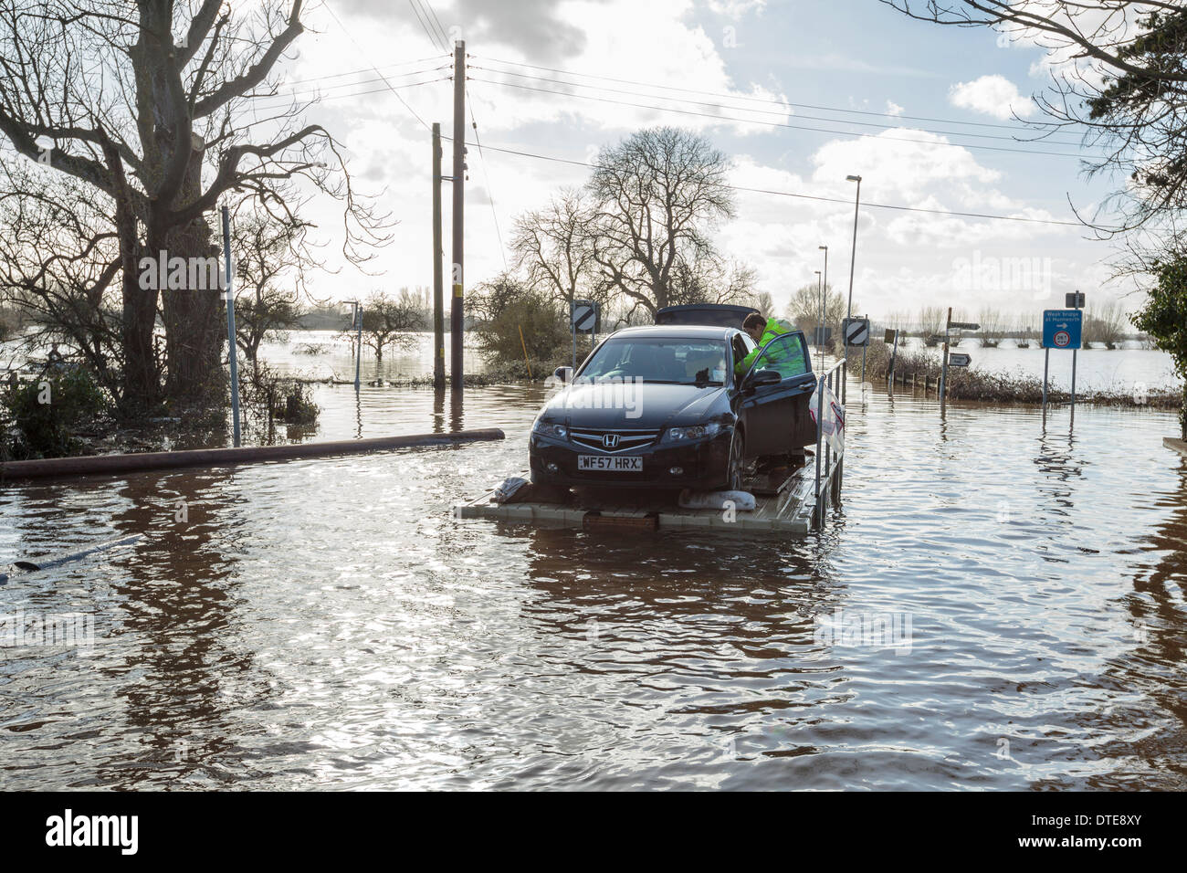 Burrowbridge, UK. 16th Feb, 2014. Volunteers rescue a Honda Accord during the heavy flooding on the Somerset Levels on February 16, 2014. The car was packed full of belongings and driven onto a pontoon used to transport vehicles and livestock and aid into the flooded community. The A361 is a major arterial route across the Somerset Levels and has just experienced the worst flooding in living history and has been underwater now for seven weeks. Credit:  Nick Cable/Alamy Live News Stock Photo