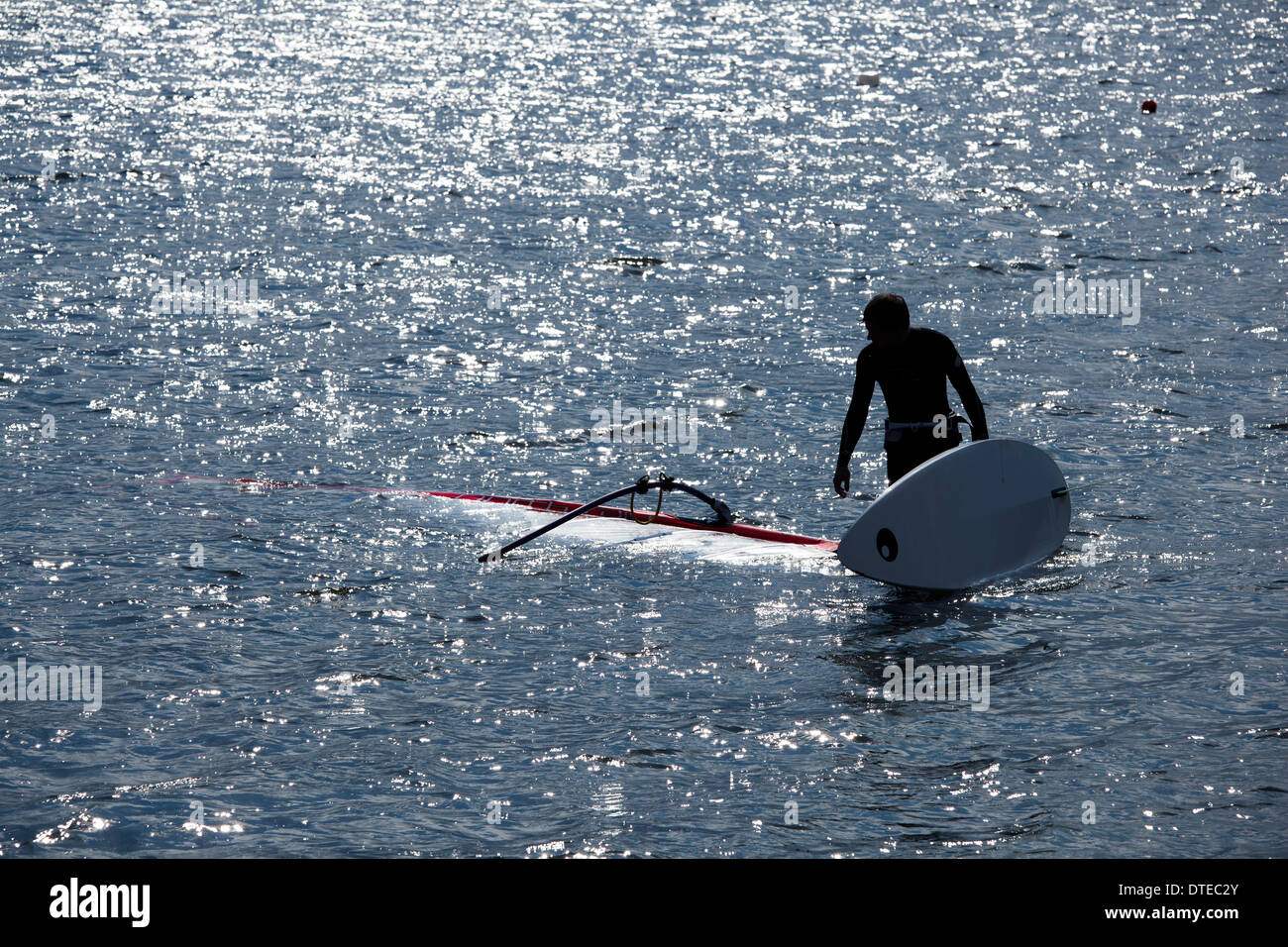 kitesurfer stands in the water, holding his surfboard Stock Photo Alamy