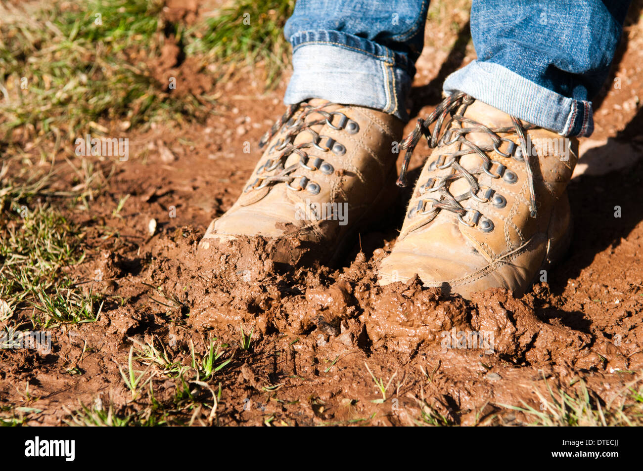 A pair of muddy walking boots stuck in fresh mud in a field in the countryside near Dartmouth in Devon Stock Photo