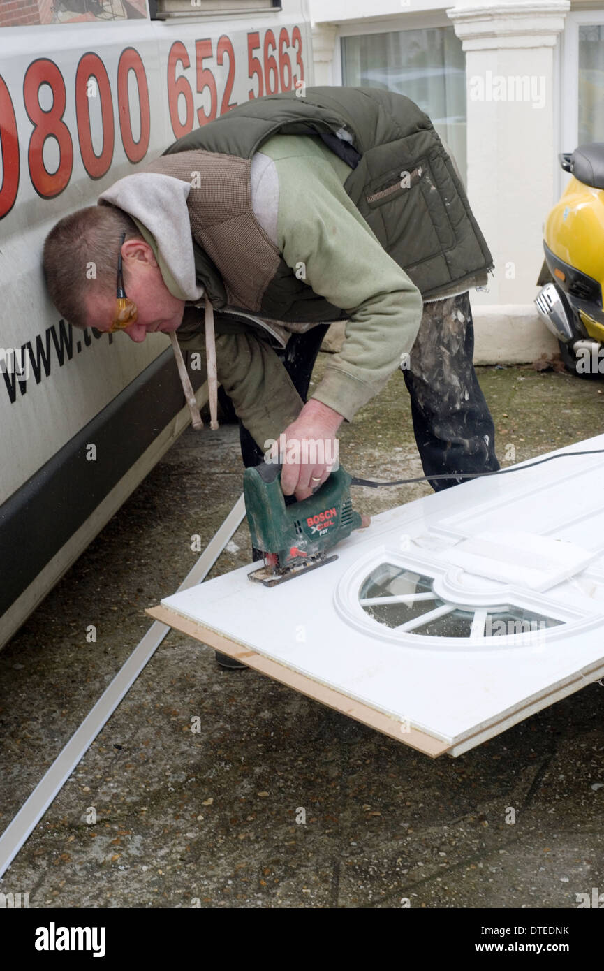 tradesman at work preparing a new door and frame for fitting at the front of a domestic house Stock Photo