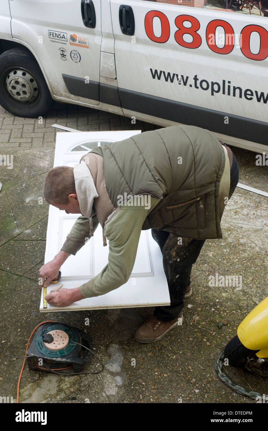 tradesman at work preparing a new door and frame for fitting at the front of a domestic house Stock Photo