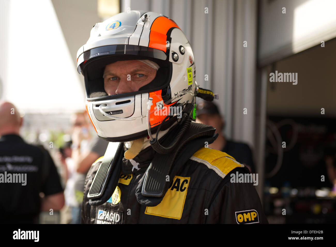 A driver in the Black Falcon 3 racing team waits for their team Porsche 997 Cup race car to come back into the pit lane Stock Photo