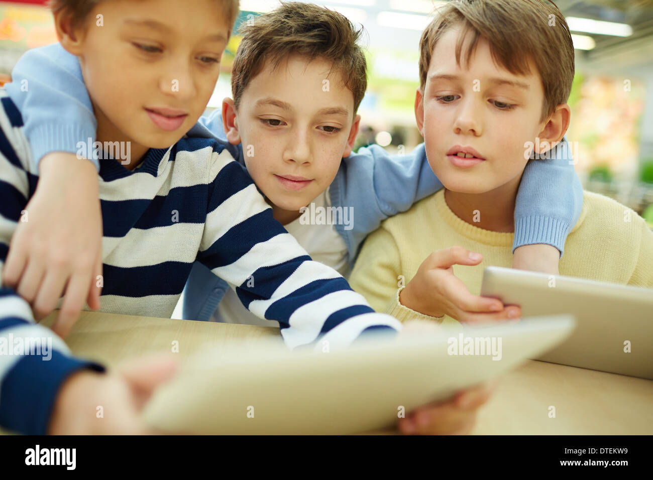 Three children sitting in cafe with touchpads Stock Photo
