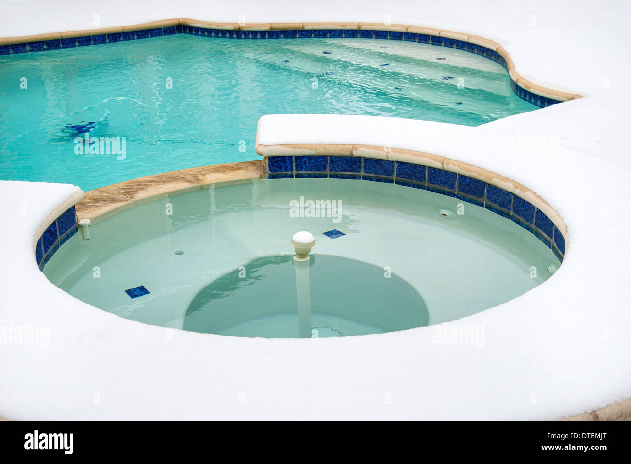 Outdoor hot tub or spa by swimming pool surrounded by snow in the winter Stock Photo