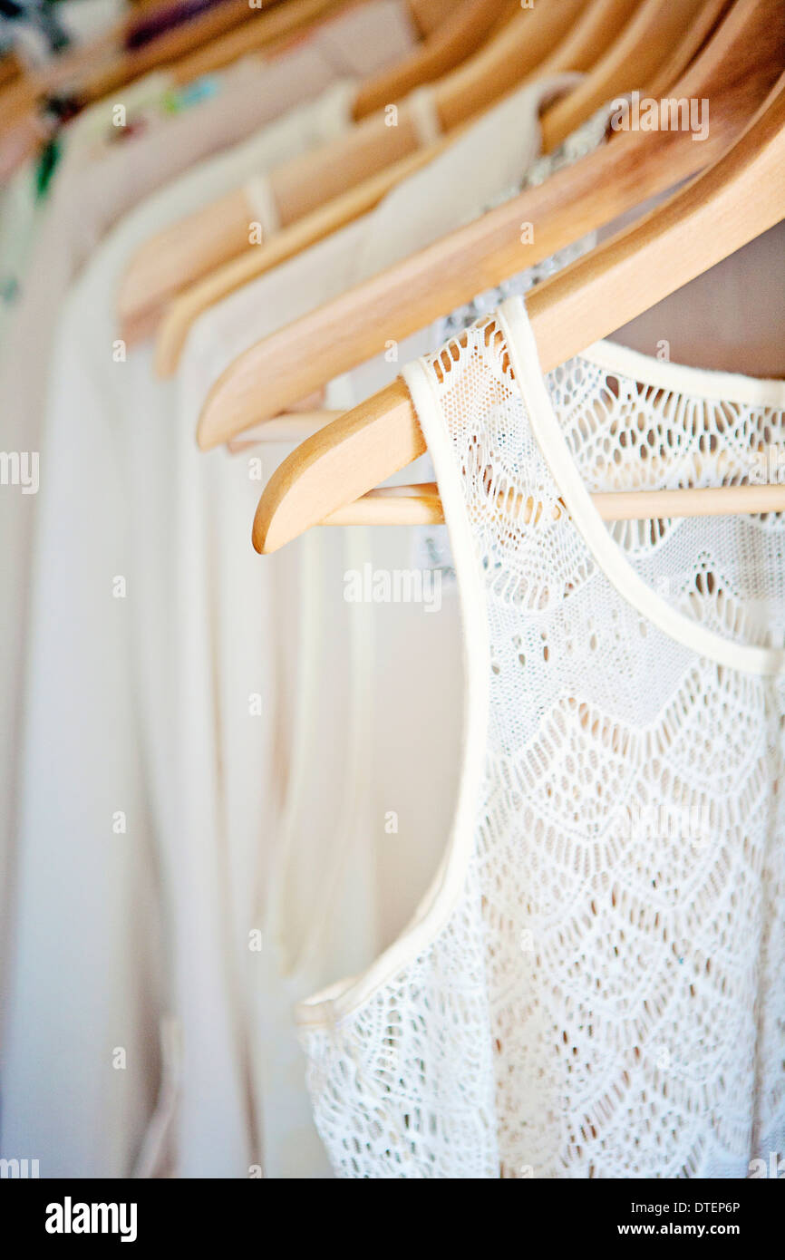 Row of white and ivory blouses on wooden hangers Stock Photo